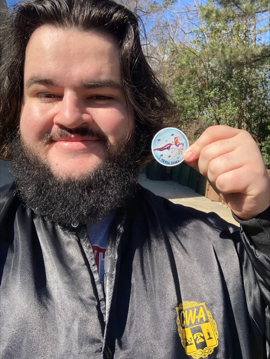 photo of smiling bearded person holding an early voting sticker 
